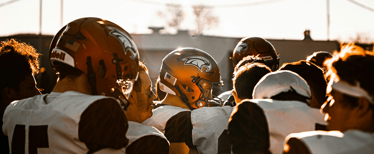 American football players huddled at golden hour